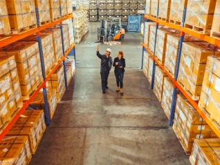 Two female workers inspecting large warehouse racks
