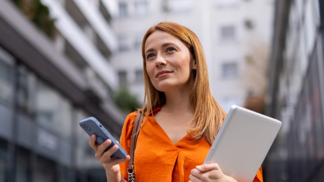 woman in orange shirt with mobile and laptop